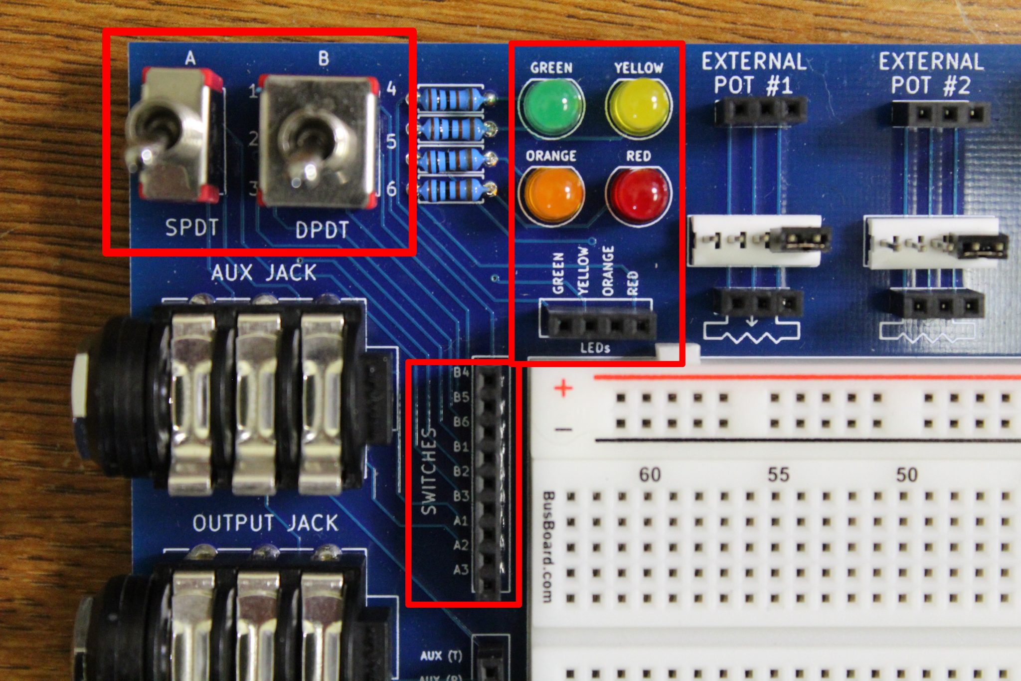 The toggle switches, LEDs, and auxiliary device header on the PROTIS 1 MINI development board.